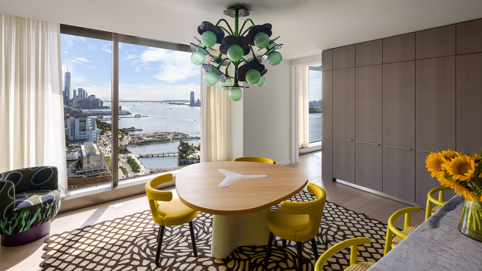 Dining area with yellow chairs and an abstract, green chandelier