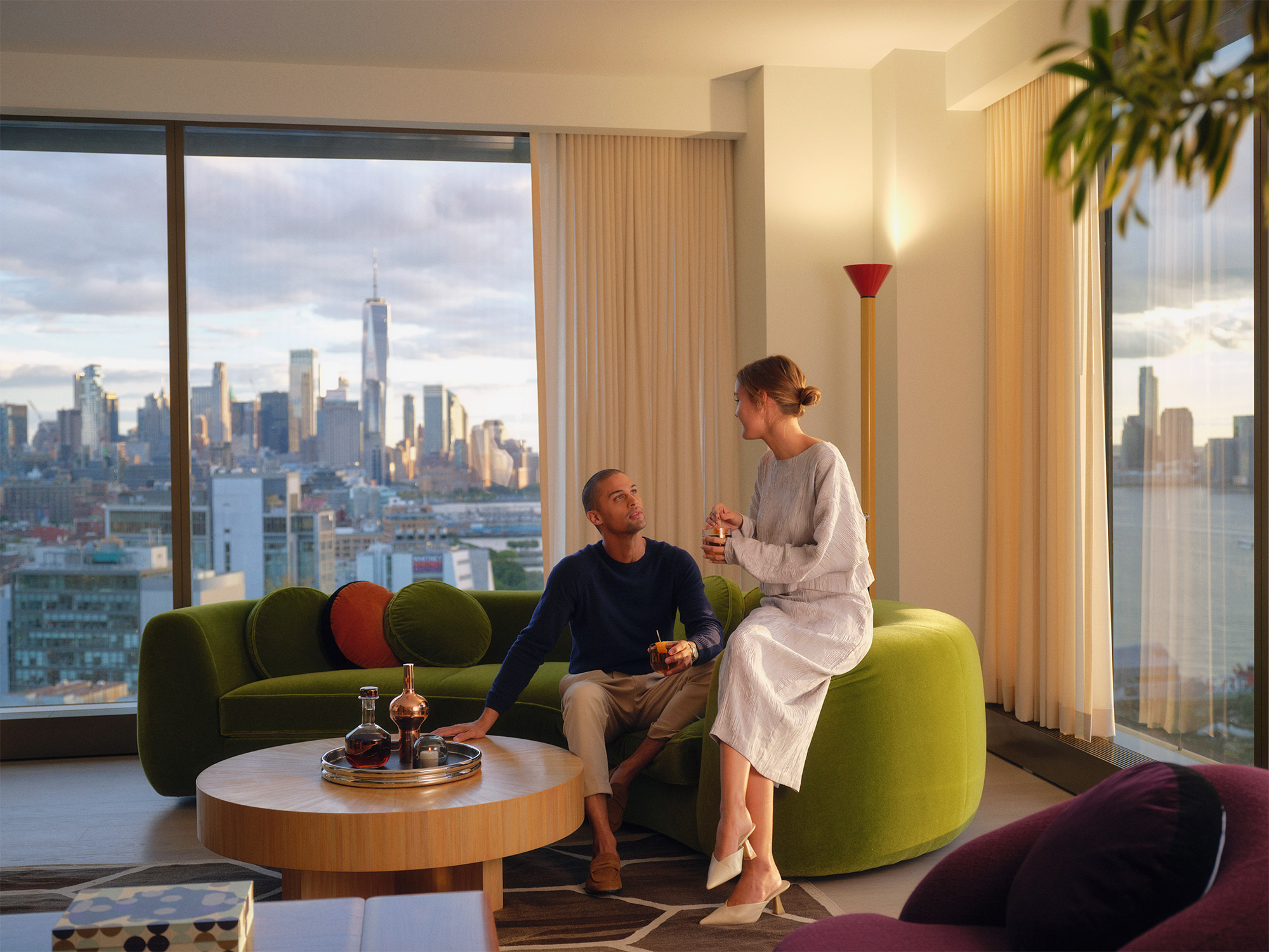 Couple sitting on green furniture with city skyline in the background