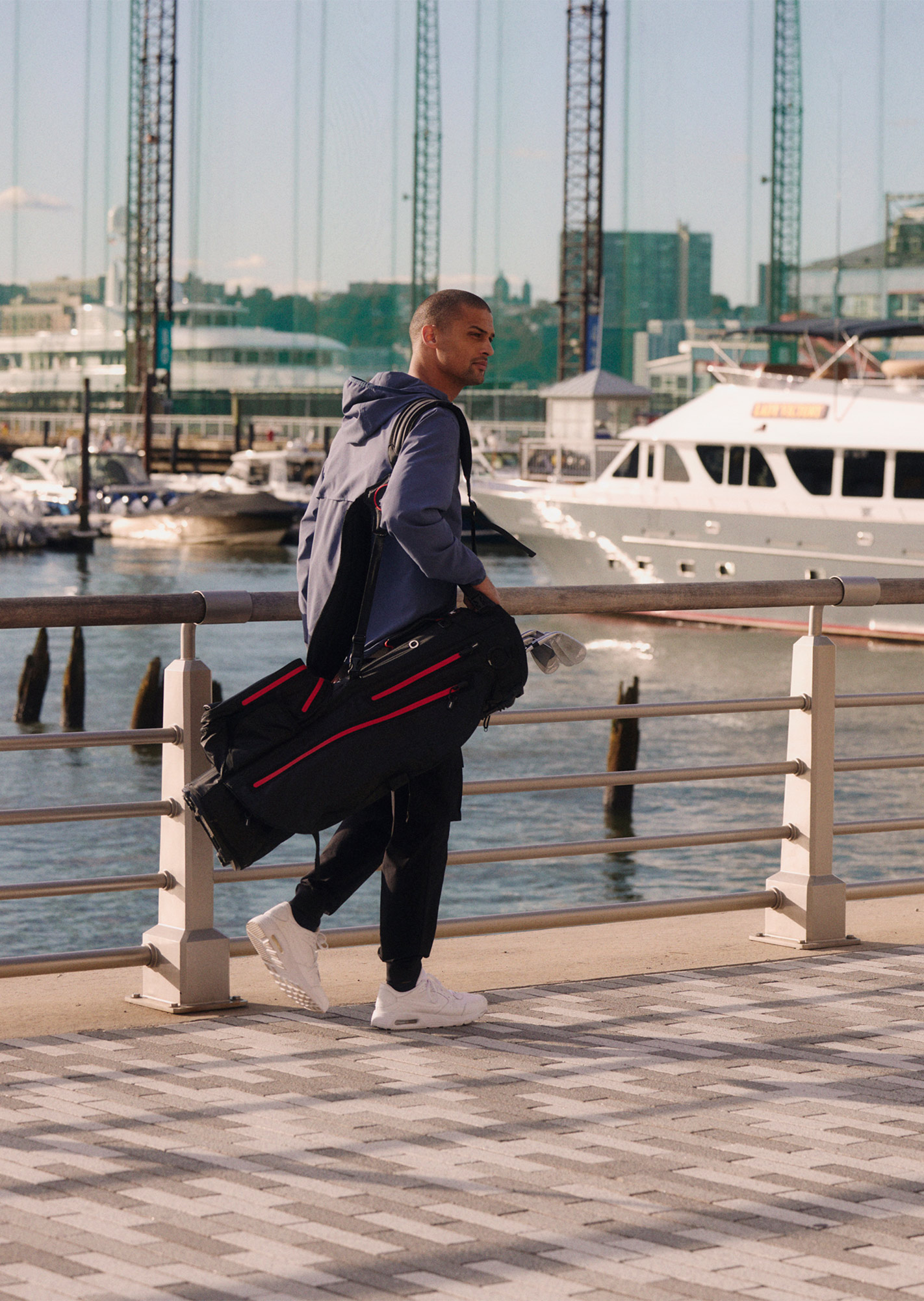 Man walking along canal, holding a Titleist golf bag