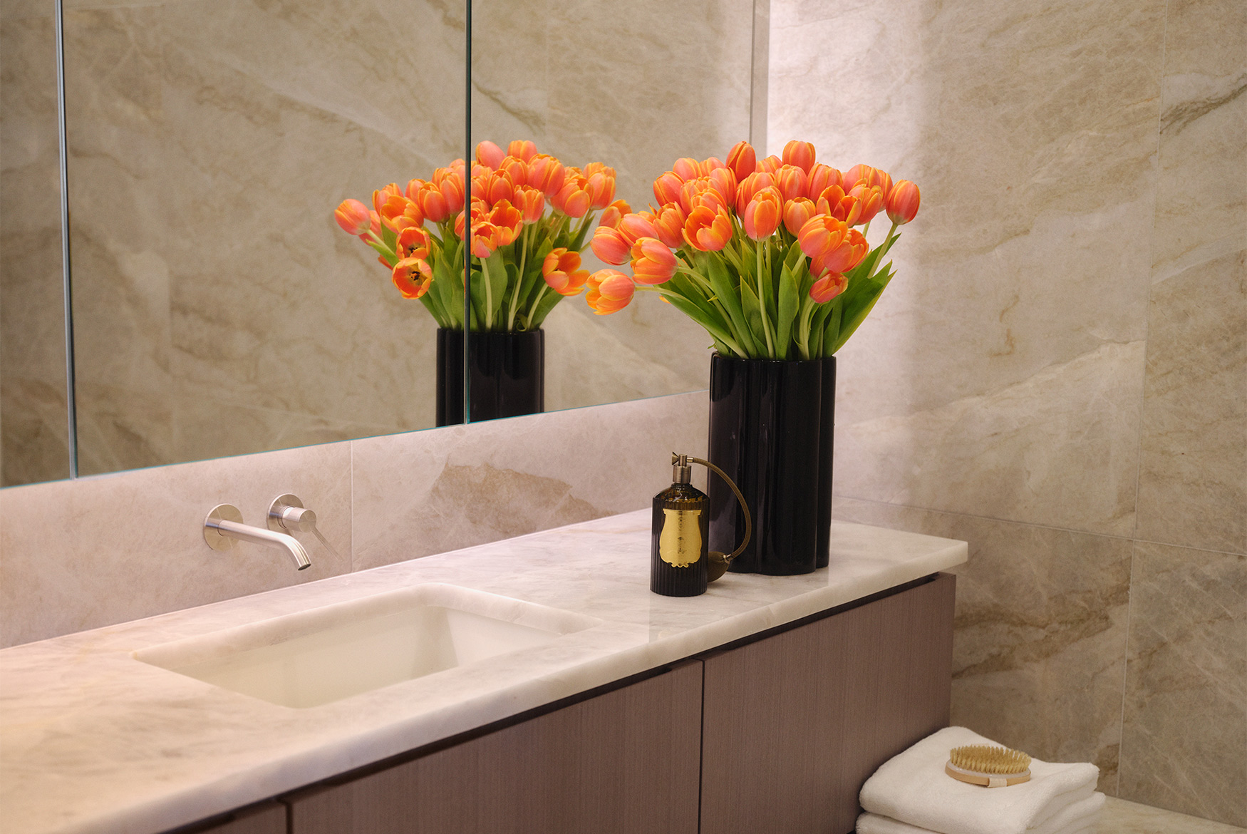orange tulips by bathroom vanity in front of a mirror